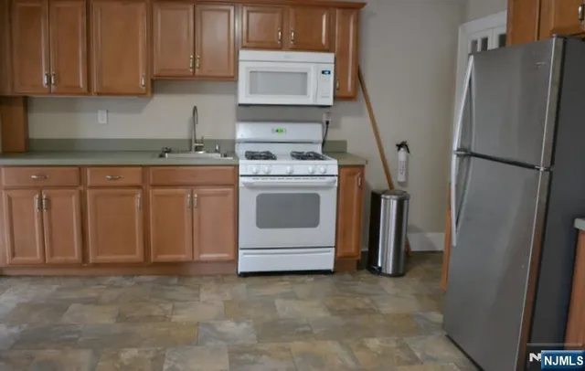 a kitchen with stainless steel appliances granite countertop a refrigerator a stove and a sink