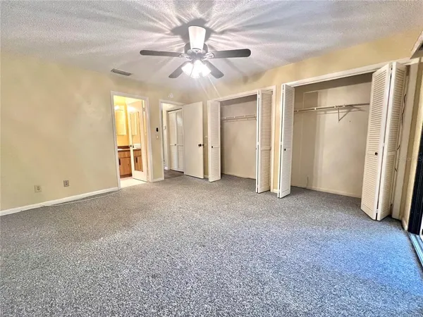 an empty room with windows and fan