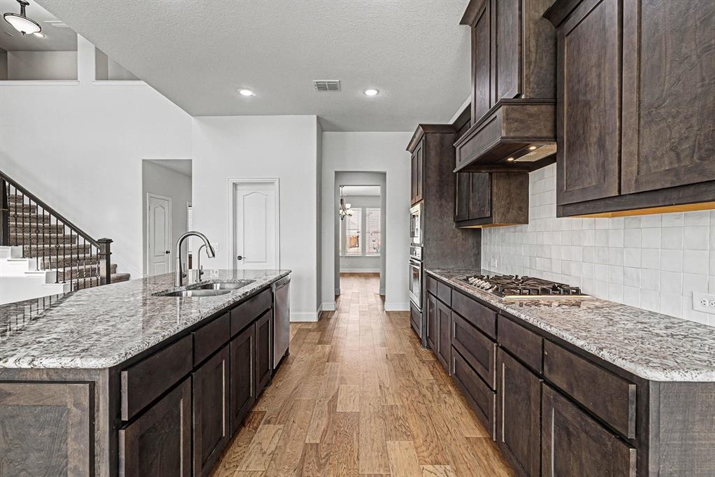 1080 Canuela Way Justin, TX 76247 - Photo 13 of 40 a kitchen with granite countertop kitchen island stainless steel appliances a sink stove top oven and cabinets