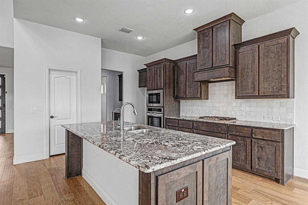 1080 Canuela Way Justin, TX 76247 - Photo 5 of 40 a kitchen with kitchen island granite countertop a sink stove and refrigerator