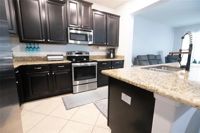 a kitchen with granite countertop a sink refrigerator and cabinets