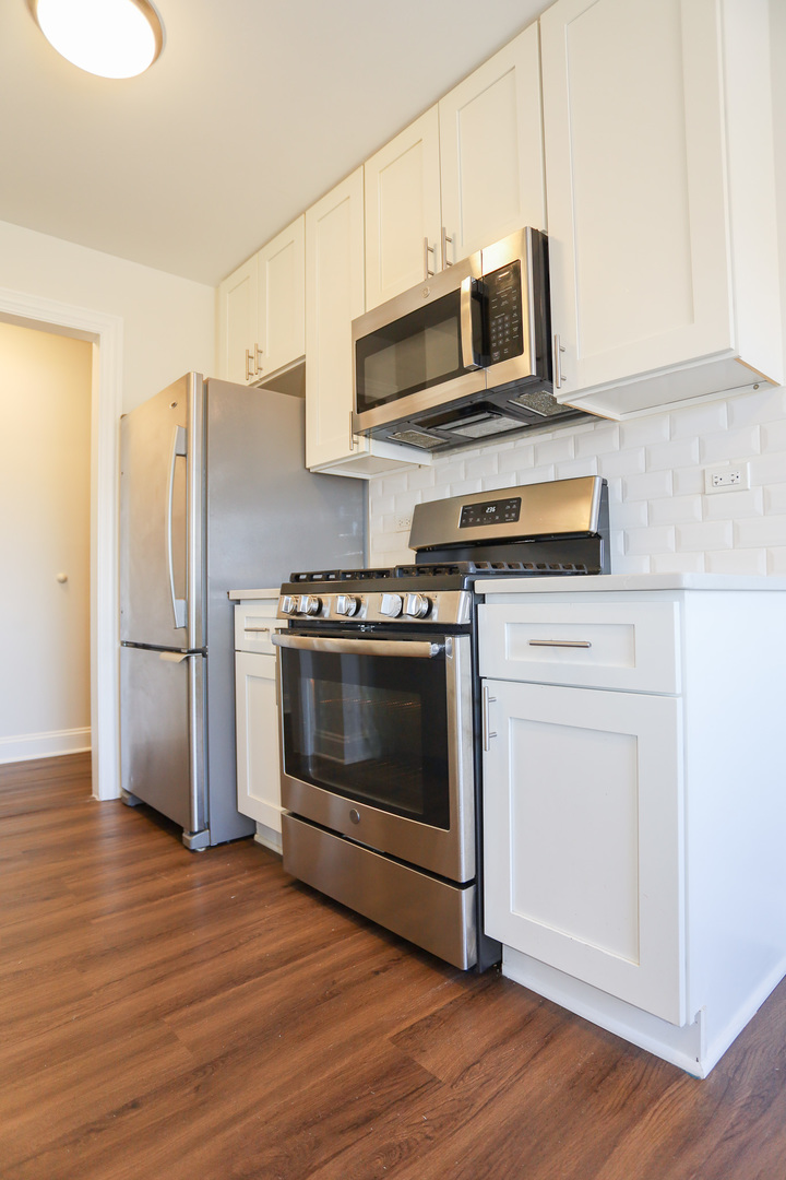 8651 West Foster Avenue, Unit 3A Chicago, IL 60656 - Photo 4 of 17 a kitchen with stainless steel appliances a stove a microwave oven cabinets and wooden floor