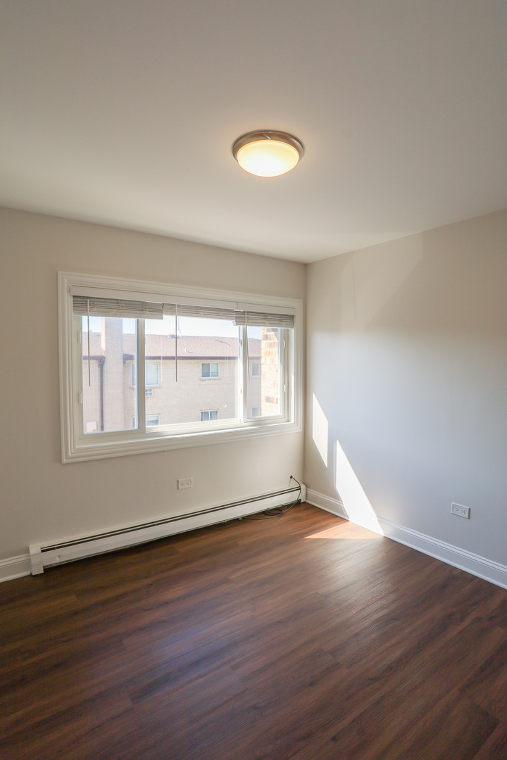 8651 West Foster Avenue, Unit 3A Chicago, IL 60656 - Photo 6 of 17 a view of an empty room with wooden floor and a window