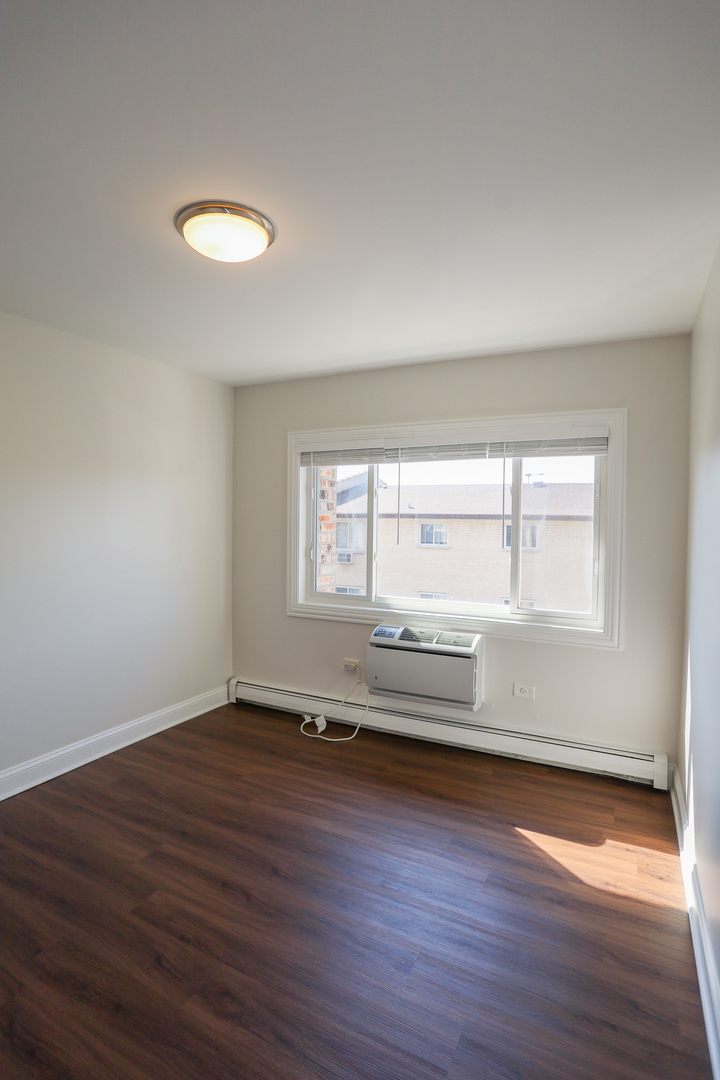8651 West Foster Avenue, Unit 3A Chicago, IL 60656 - Photo 9 of 17 an empty room with wooden floor and windows
