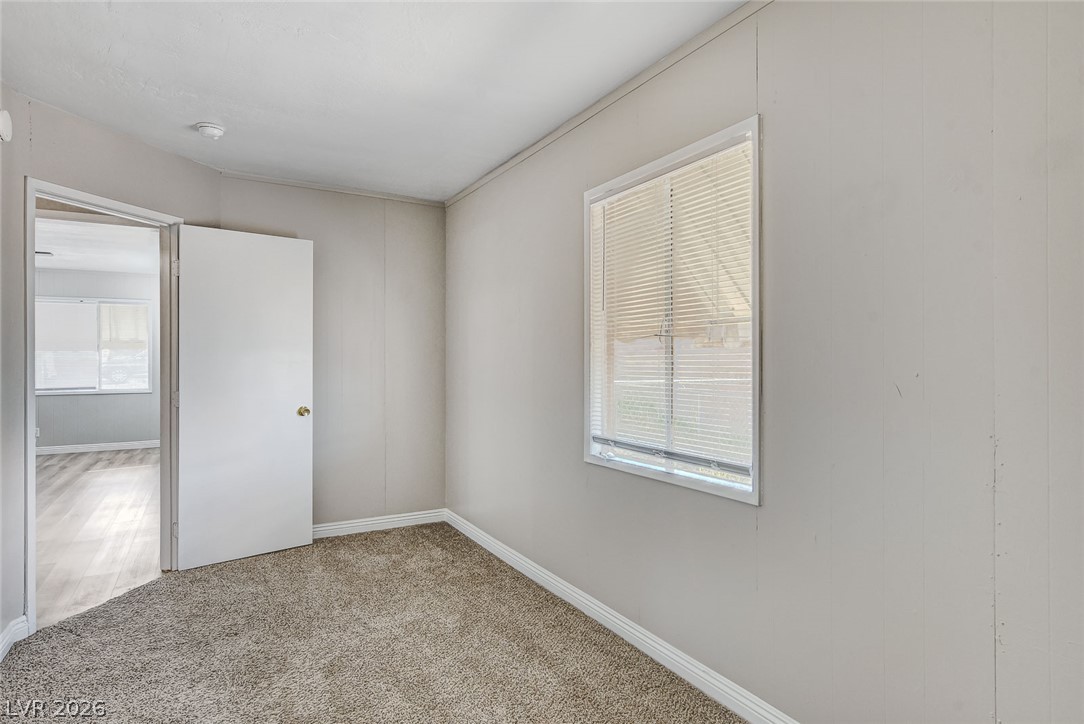 214 West Victory Road Henderson, NV 89015 - Photo 19 of 33 A well-lit bedroom features plush carpeting and a clear window, offering a comfortable personal retreat.