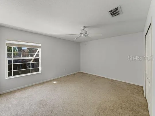 an empty room with windows and ceiling fan
