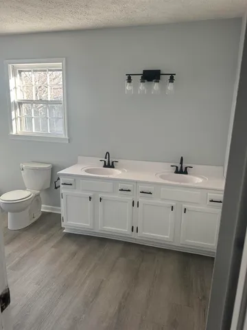 a bathroom with a double vanity sink a toilet and a window