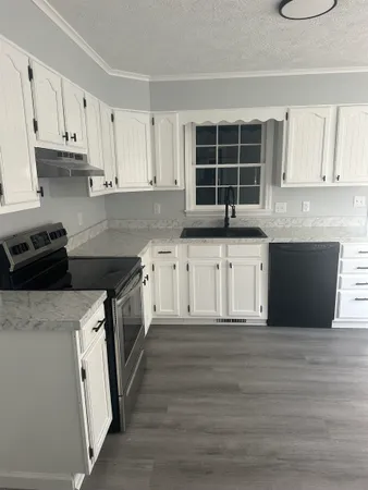 a kitchen with granite countertop a stove sink and cabinets