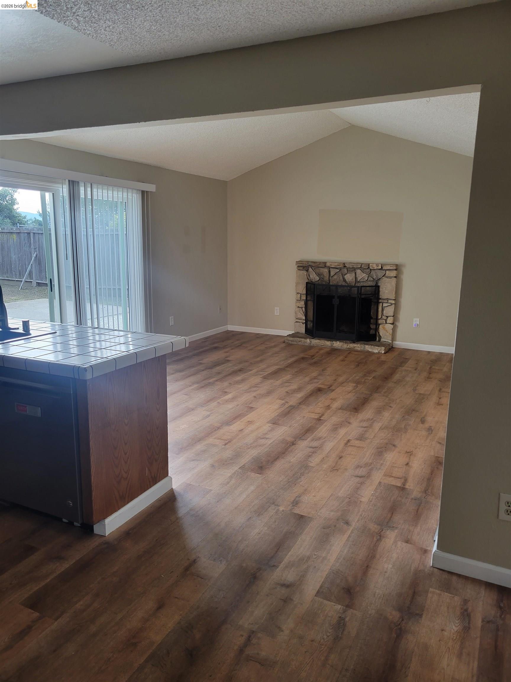 906 Coral Drive Rodeo, CA 94572 - Photo 7 of 21 an empty room with wooden floor and fireplace