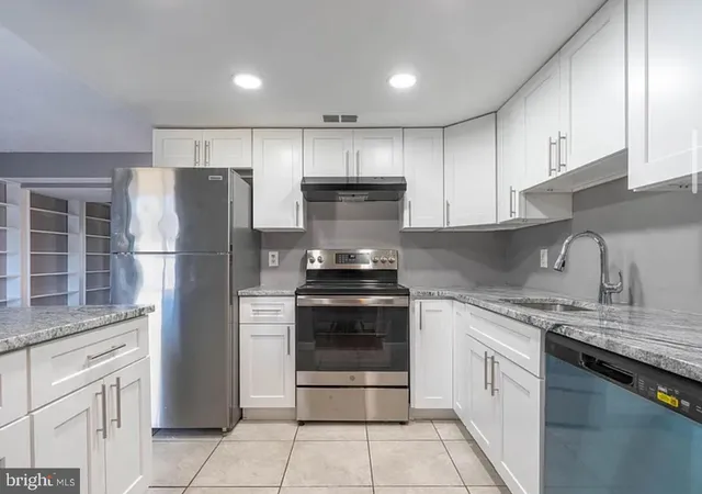 a kitchen with stainless steel appliances granite countertop a refrigerator stove and cabinets