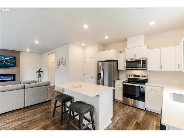 a kitchen with stainless steel appliances a sink a stove a refrigerator cabinets and a dining table