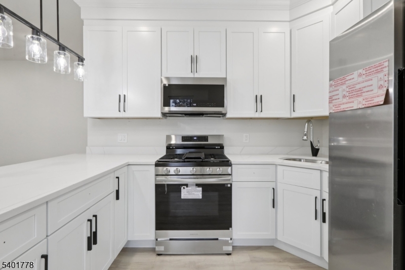 540 East 25th Street Paterson, NJ 07514 - Photo 3 of 10 a kitchen with white cabinets stainless steel appliances and sink
