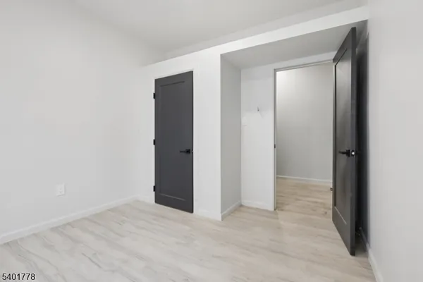 a view of an empty room with closet and wooden floor