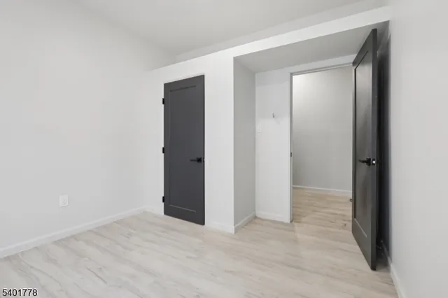 a view of an empty room with closet and wooden floor