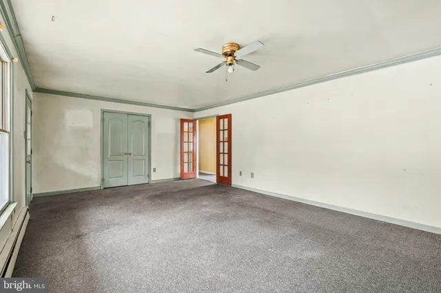an empty room with chandelier fan and windows