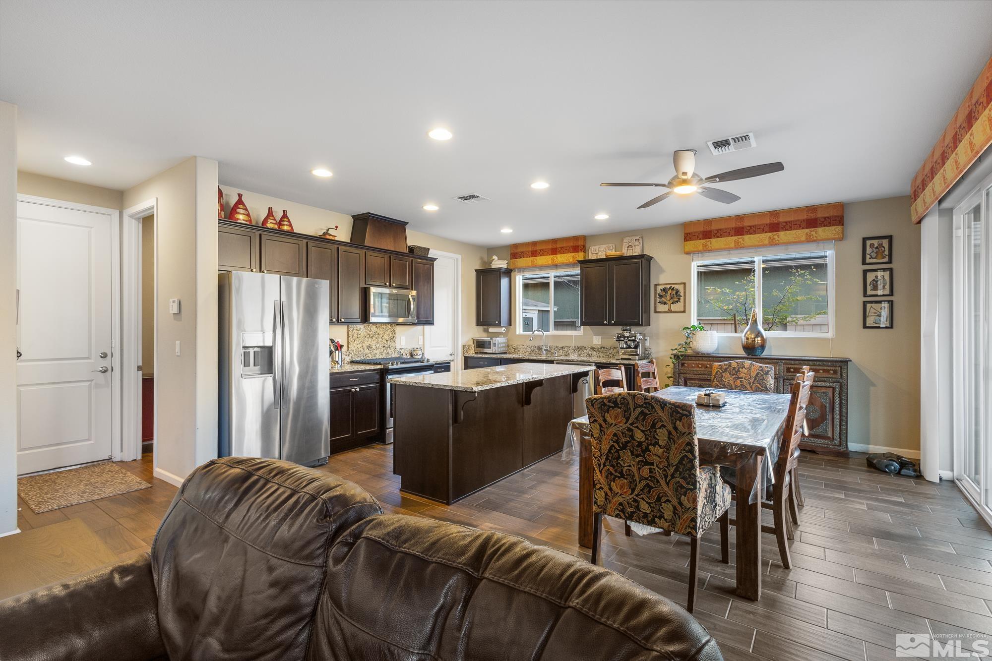 2875 Bonfire Lane Reno, NV 89521 - Photo 7 of 39 a kitchen with stainless steel appliances granite countertop a refrigerator a stove a sink dishwasher a dining table and chairs with wooden floor