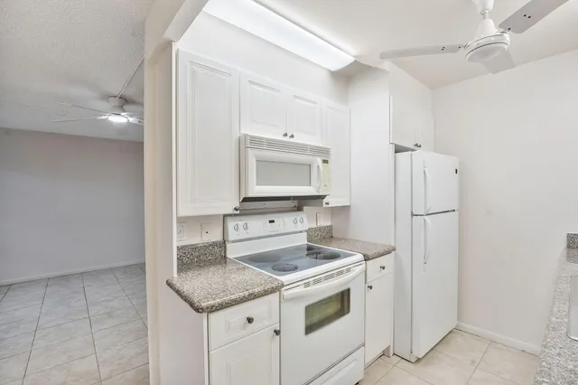 an empty room with wooden floor chandelier fan and windows