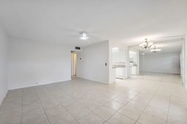 an empty room with windows and chandelier fan