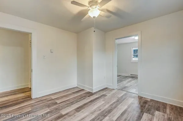 an empty room with wooden floor and fan
