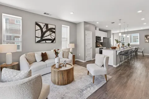 a living room with furniture kitchen view and a wooden floor