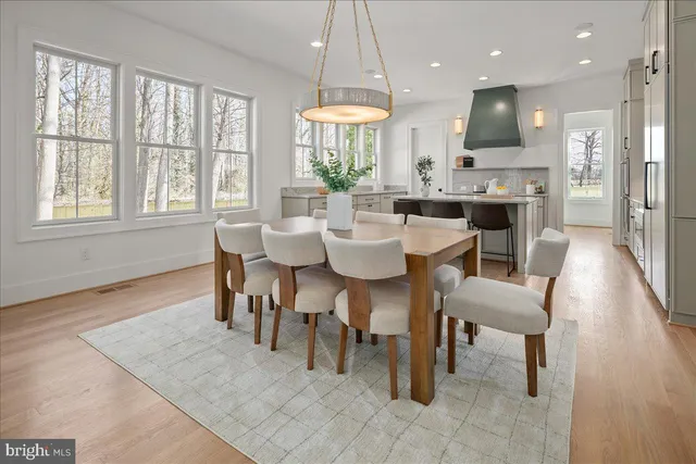 a dining room with wooden floor a chandelier a glass table and chairs