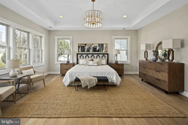 a spacious bedroom with a bed a table and large windows