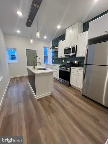 a kitchen with stainless steel appliances granite countertop a refrigerator a stove a sink dishwasher and a oven with wooden floor