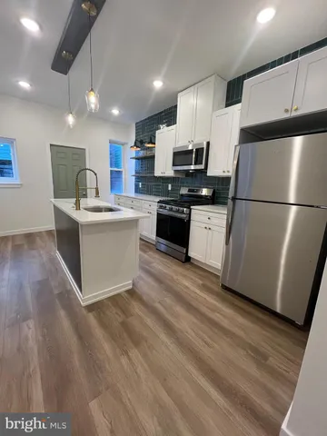 a kitchen with a refrigerator a stove top oven a sink dishwasher and a refrigerator with wooden floor