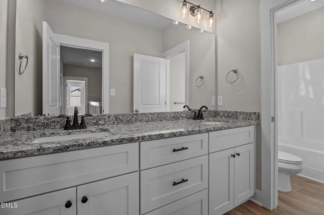 a bathroom with a granite countertop sink mirror vanity and toilet