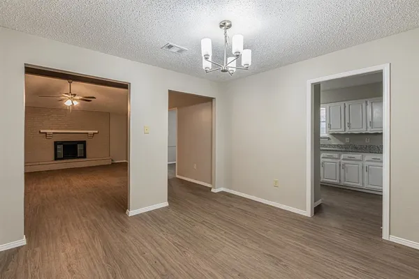 a view of a livingroom with a fireplace wooden floor and kitchen view