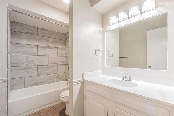 a bathroom with a bathtub shower sink vanity and toilet