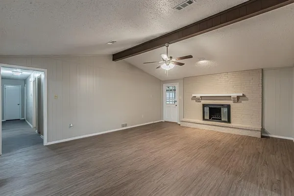 an empty room with wooden floor fireplace and windows
