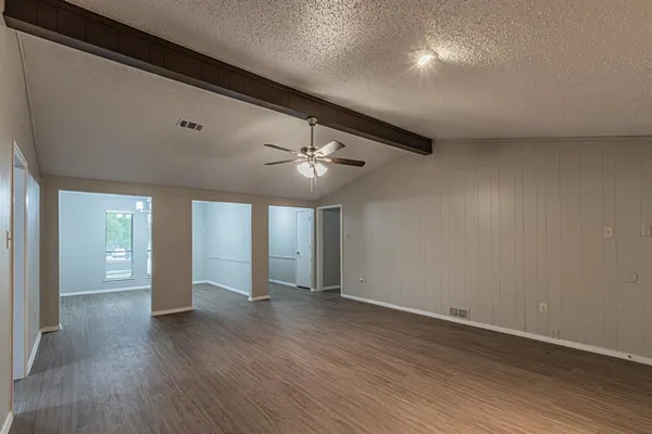 an empty room with wooden floor and windows