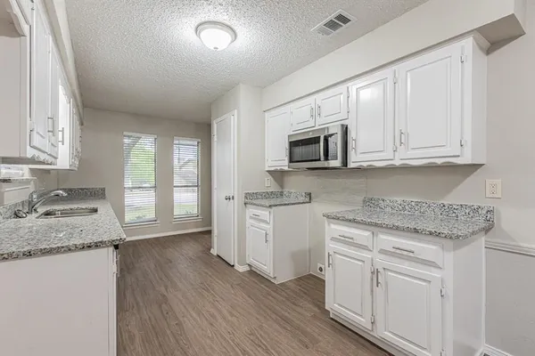 a kitchen with granite countertop white cabinets and white appliances