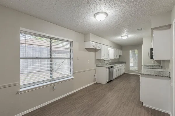 a kitchen with stainless steel appliances wooden floors and white cabinets