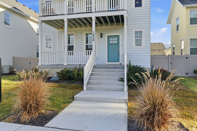 1038 South Old Towne Road Layton, UT 84041 - Photo 39 of 39 Light blue siding exterior featuring multiple balconies with white railings, a turquoise front door, and a concrete pathway leading to the entrance