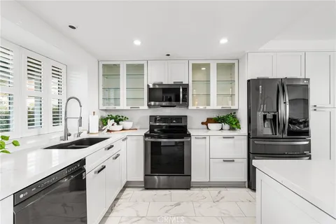 a kitchen with stainless steel appliances a sink a window and cabinets
