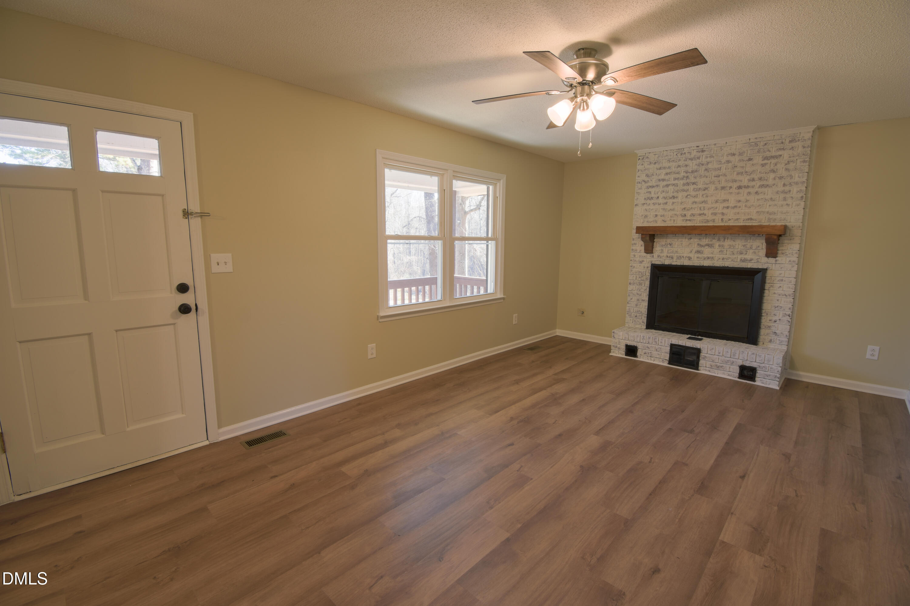 1412 Chamblee Road Zebulon, NC 27597 - Photo 5 of 22 a view of a livingroom with a fireplace a ceiling fan and wooden floor