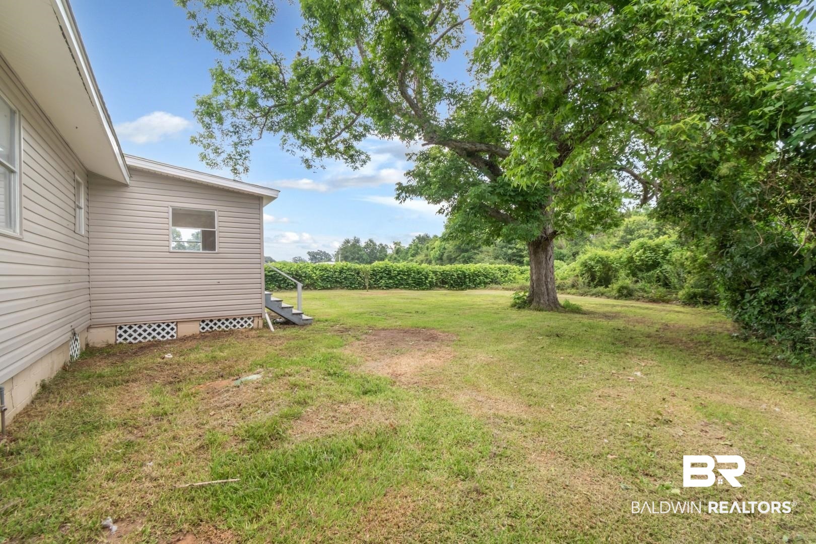 2905A McFarland Road, Unit F Mobile, AL 36695 - Photo 2 of 29 Expansive grassy yard featuring a prominent mature tree, vinyl siding exterior, and exterior steps with railing