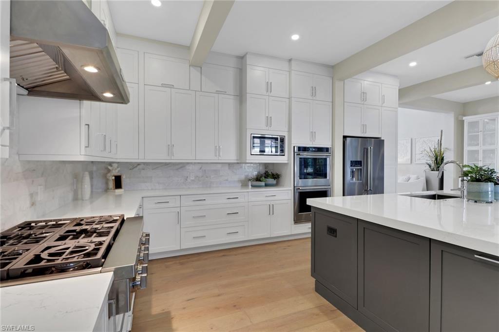 2127 Harlans Run Naples, FL 34105 - Photo 7 of 22 a kitchen with kitchen island white cabinets and stainless steel appliances