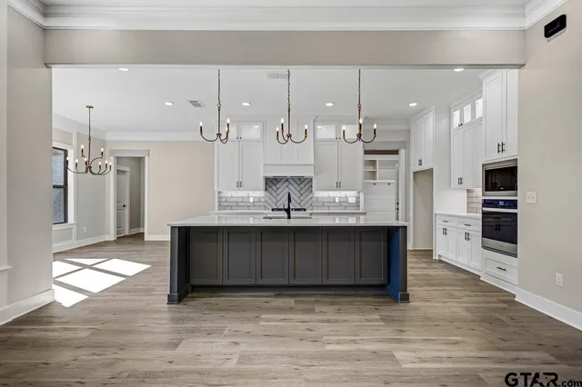 a large kitchen with stainless steel appliances a large counter top a stove a refrigerator and a cabinets