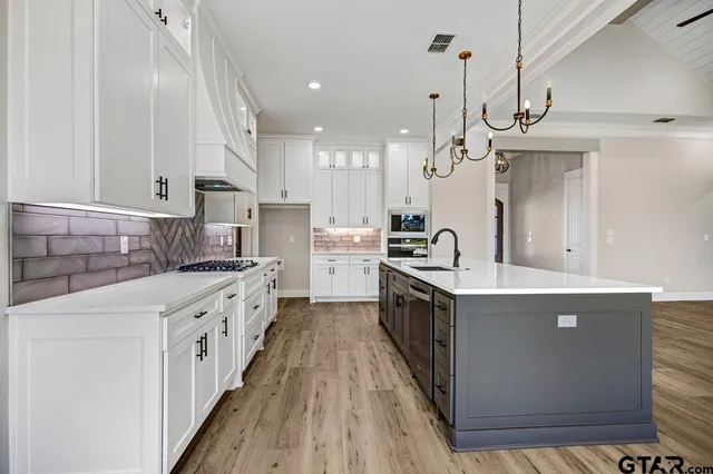 a kitchen with granite countertop a sink a counter top space stainless steel appliances and cabinets