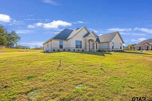a view of a house with a big yard and large trees
