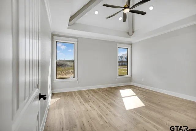 an empty room with wooden floor fan and windows