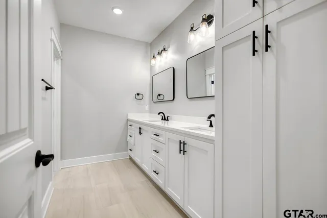 a spacious bathroom with a double vanity sink a mirror and shower