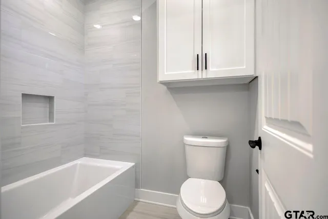 a white toilet sitting next to a bathtub