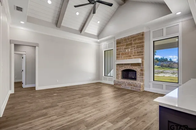 an empty room with wooden floor a fireplace and windows
