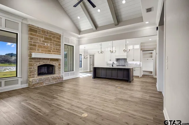 a view of a livingroom with a fireplace a ceiling fan and windows