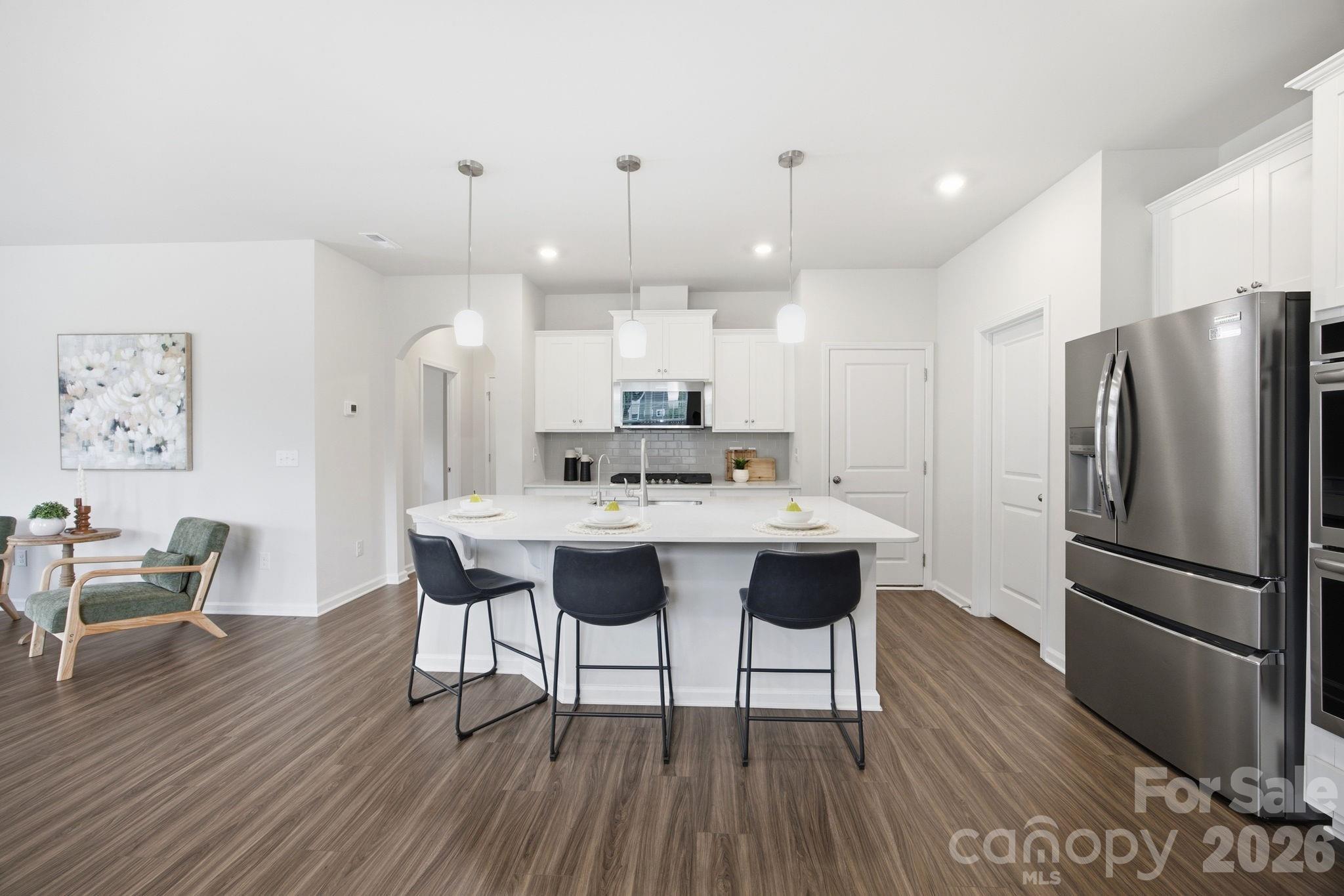 234 Hamptons Cove Road Troutman, NC 28166 - Photo 7 of 32 a kitchen with stainless steel appliances a dining table chairs and wooden floor