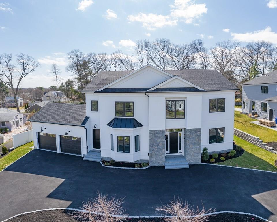 a view of a white house next to a yard with plants and large trees